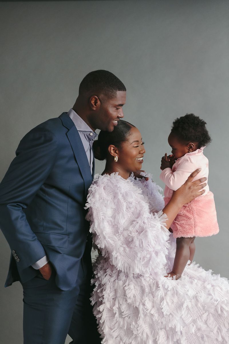 a black couple dressed elegantly look at their child during a studio session by Paula Ortiz NYC Family Photographer