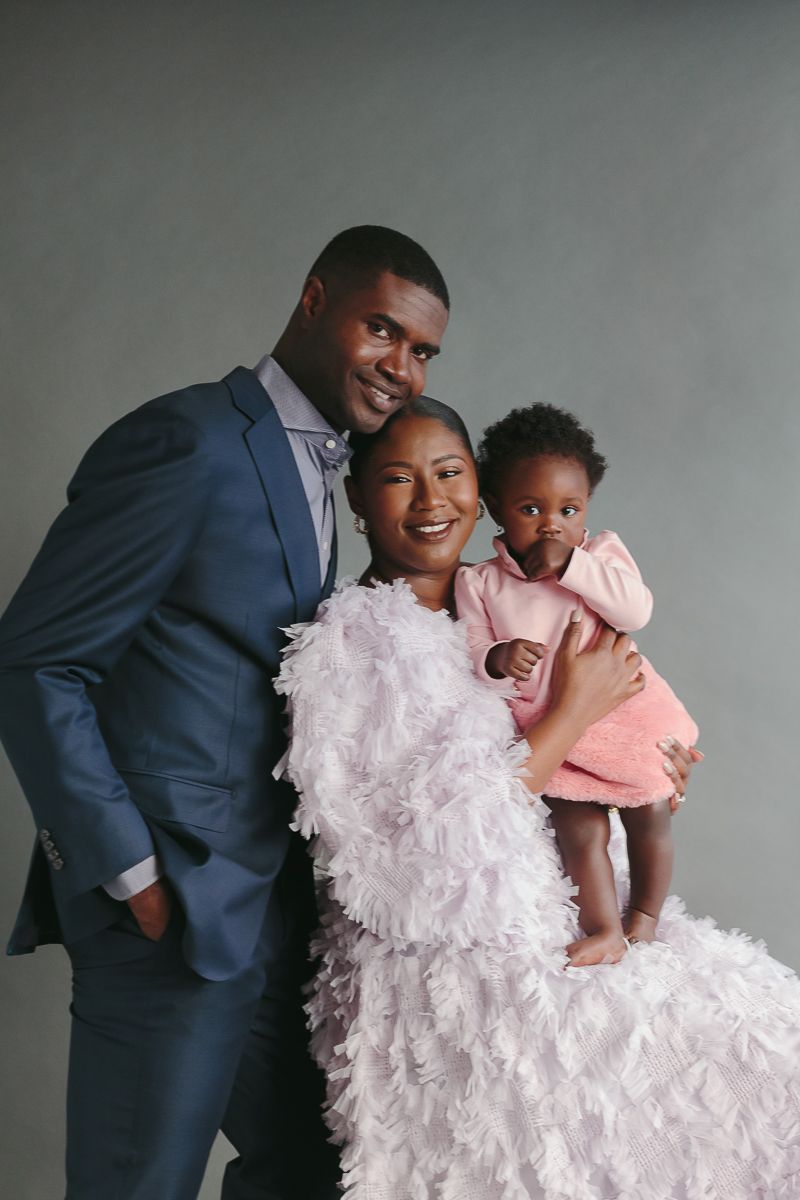 a family of three dressed elegantly look at the camera during a studio session by Paula Ortiz NYC Family Photographer