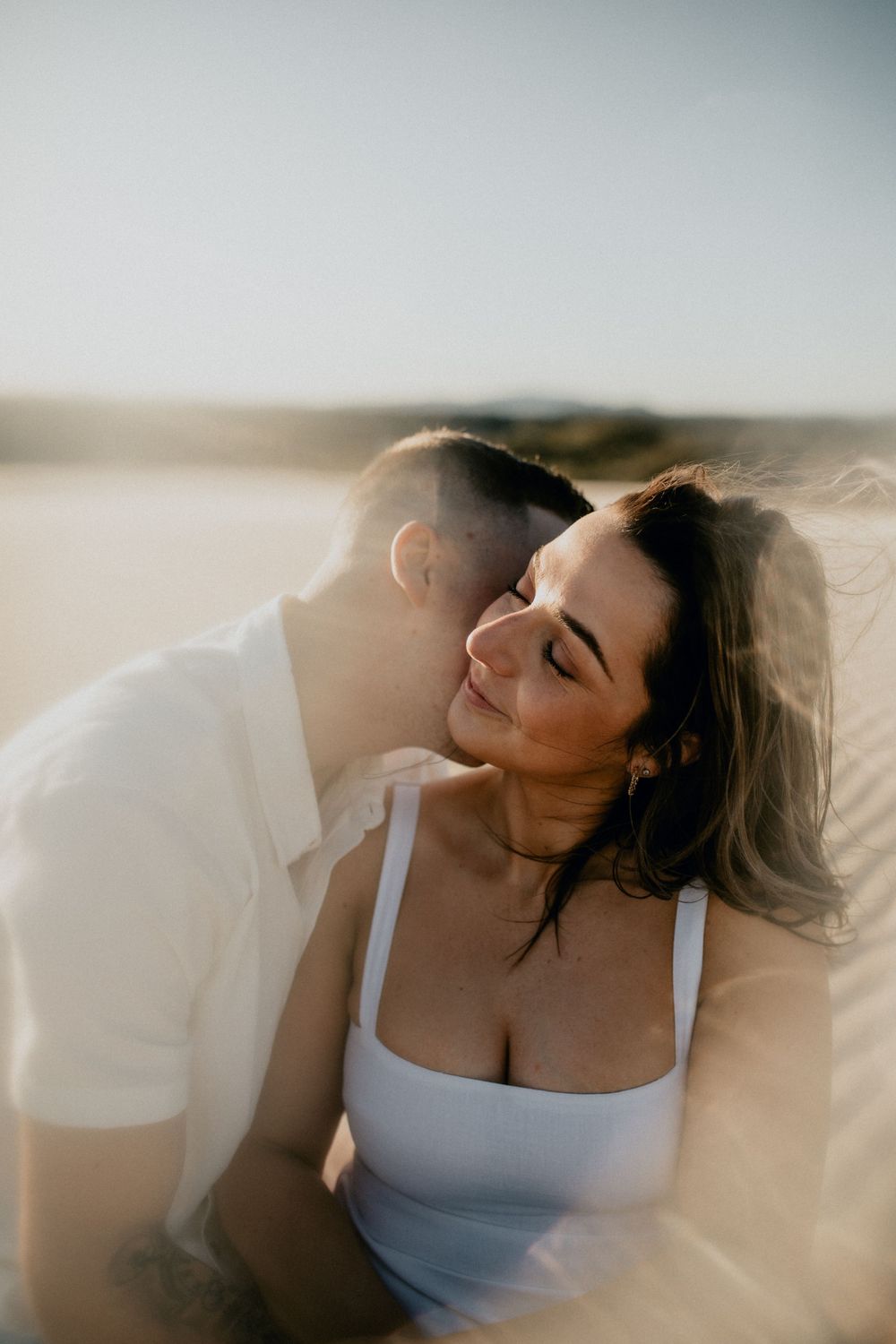 Intimate couple moment captured in warm golden light with desert backdrop.