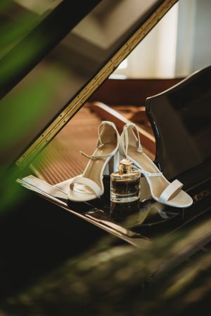 White bridal heels photographed through greenery on reflective surface.