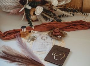 Rustic wedding details featuring brown leather, feathers and invitation cards.
