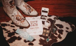 Western boots and save the date cards displayed on cowhide rug.
