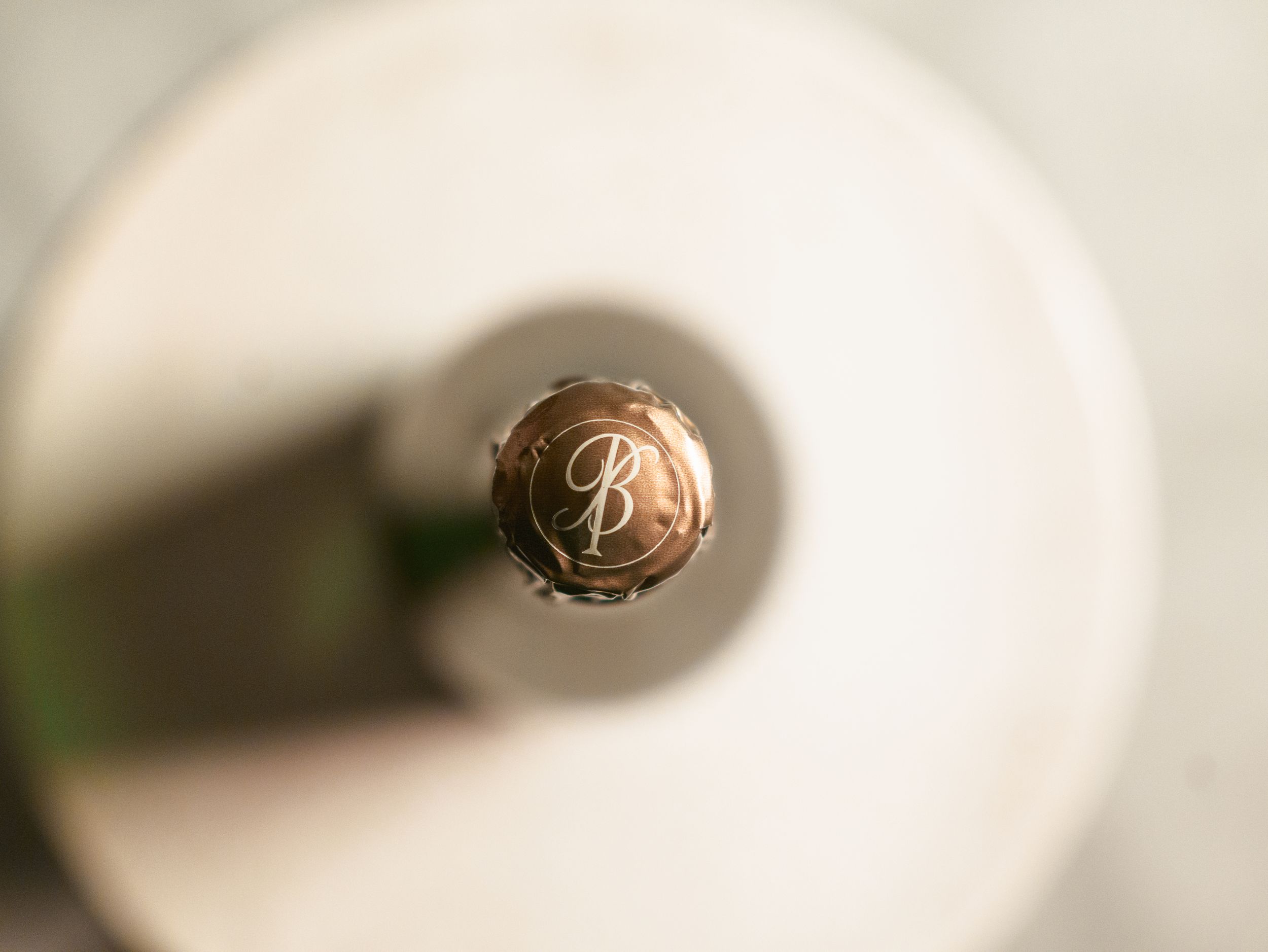 Close-up overhead view of champagne bottle cap with embossed logo.