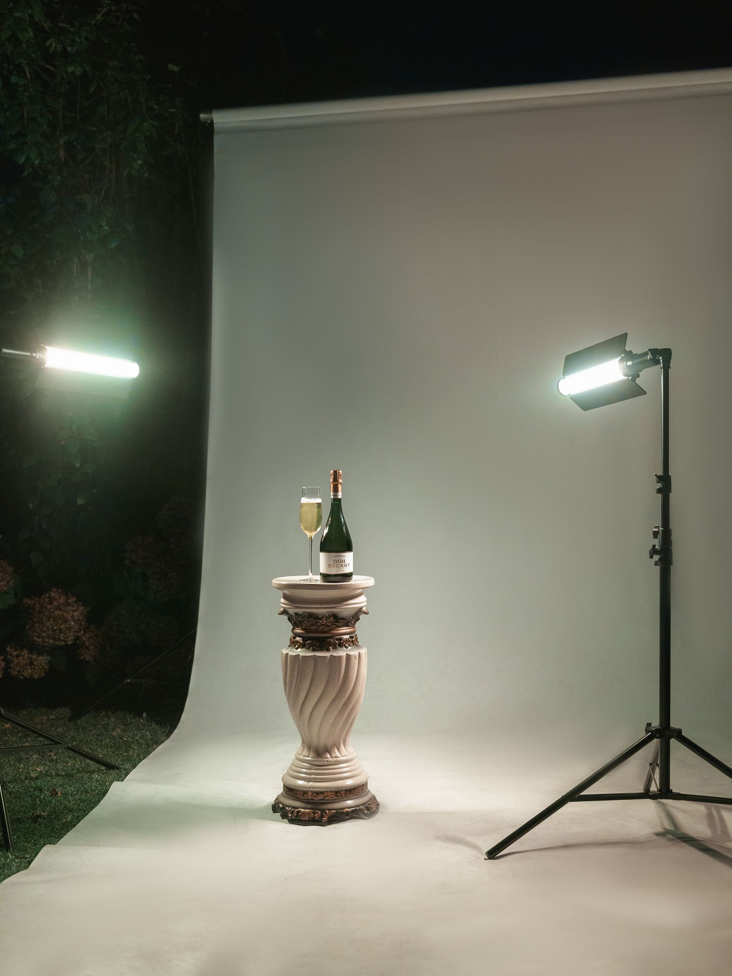 Professional photo studio setup with lighting and pedestal against white backdrop.