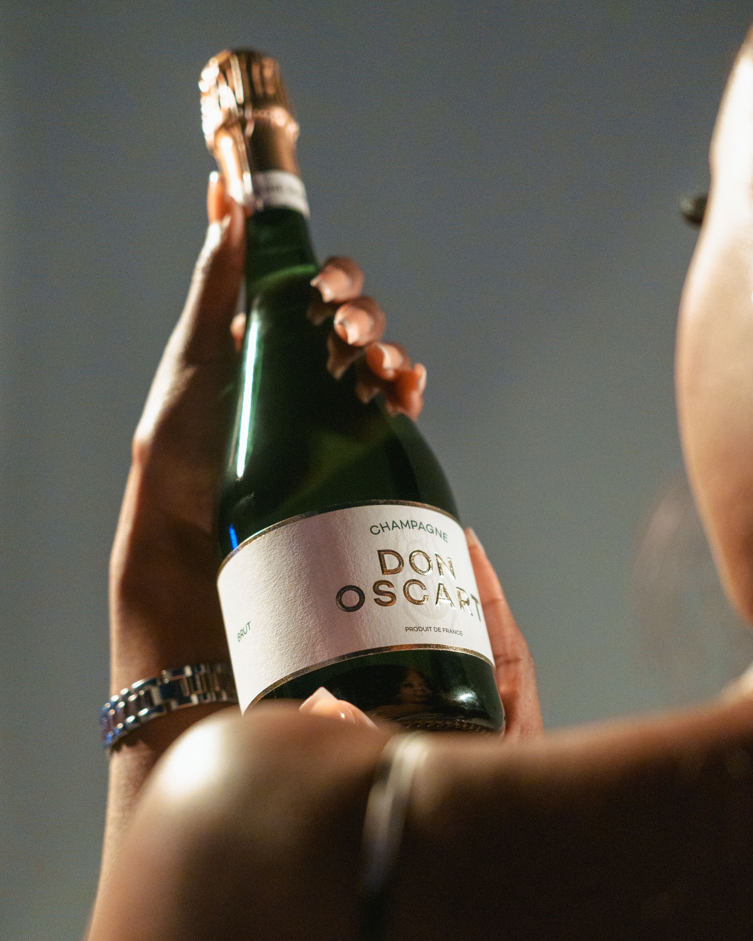 Artistic shot of champagne bottle being held against dark background.
