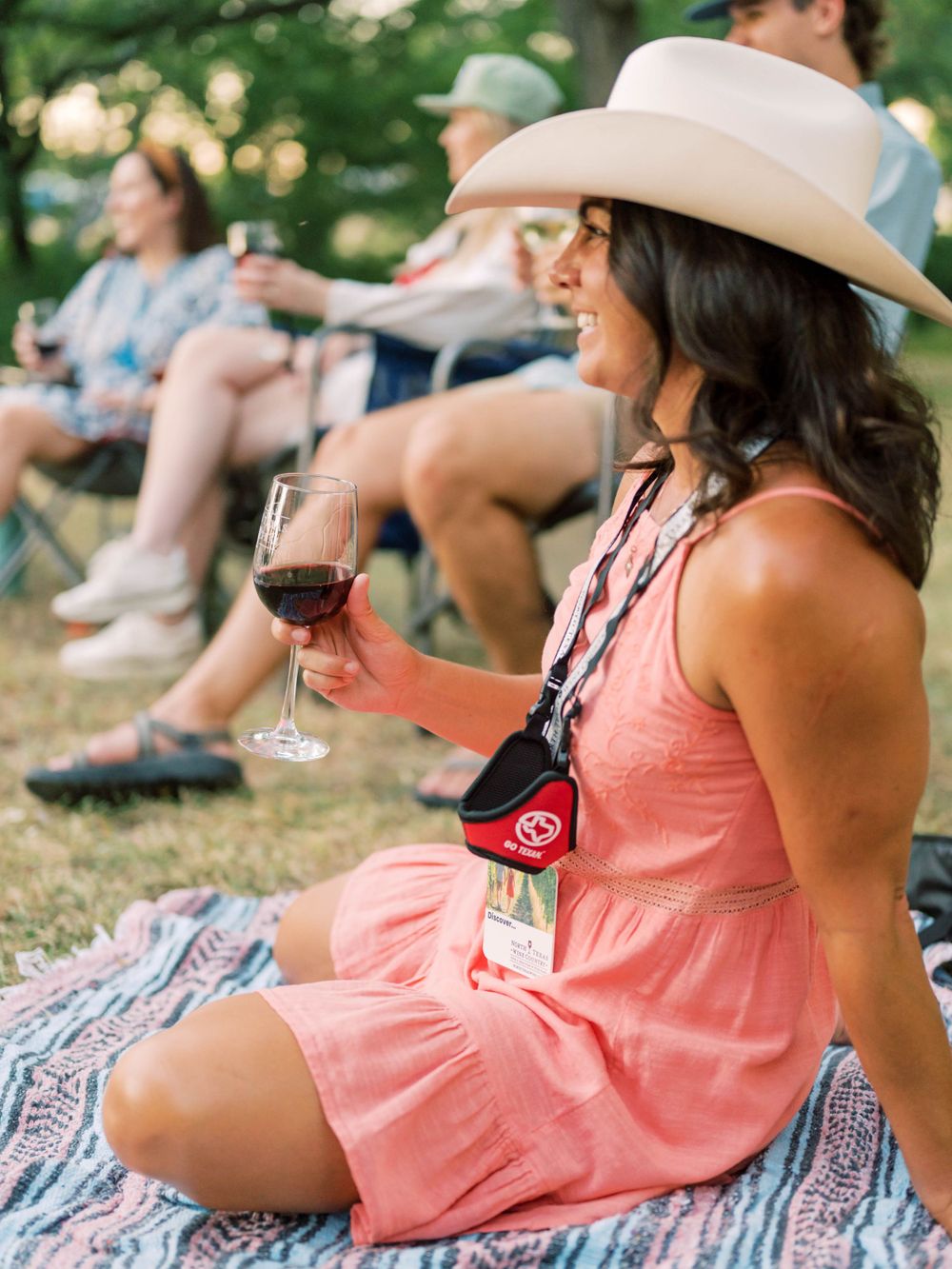 event photo of a woman in a cowgirl hat holding a glass of wine at an outdoor concert