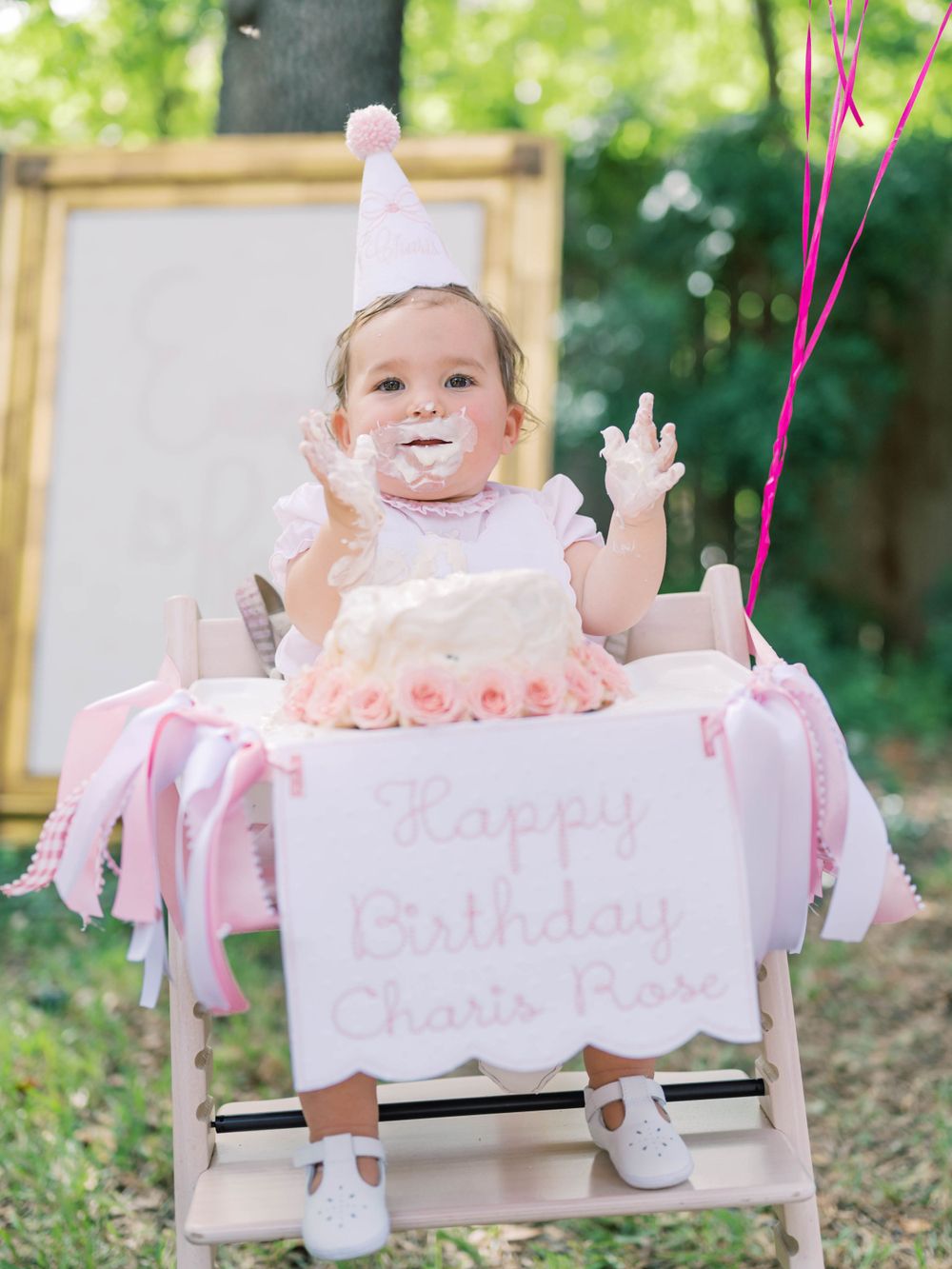 little girl with cake on her face celebrating her first birthday