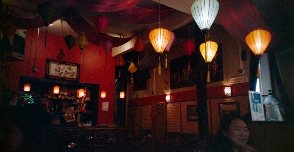 Colorful Asian paper lanterns hanging in a dimly lit red restaurant interior.