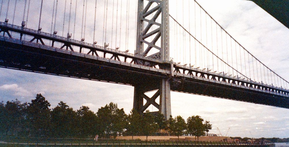 Low angle view of Benjamin Franklin Bridge spanning across water during sunset.