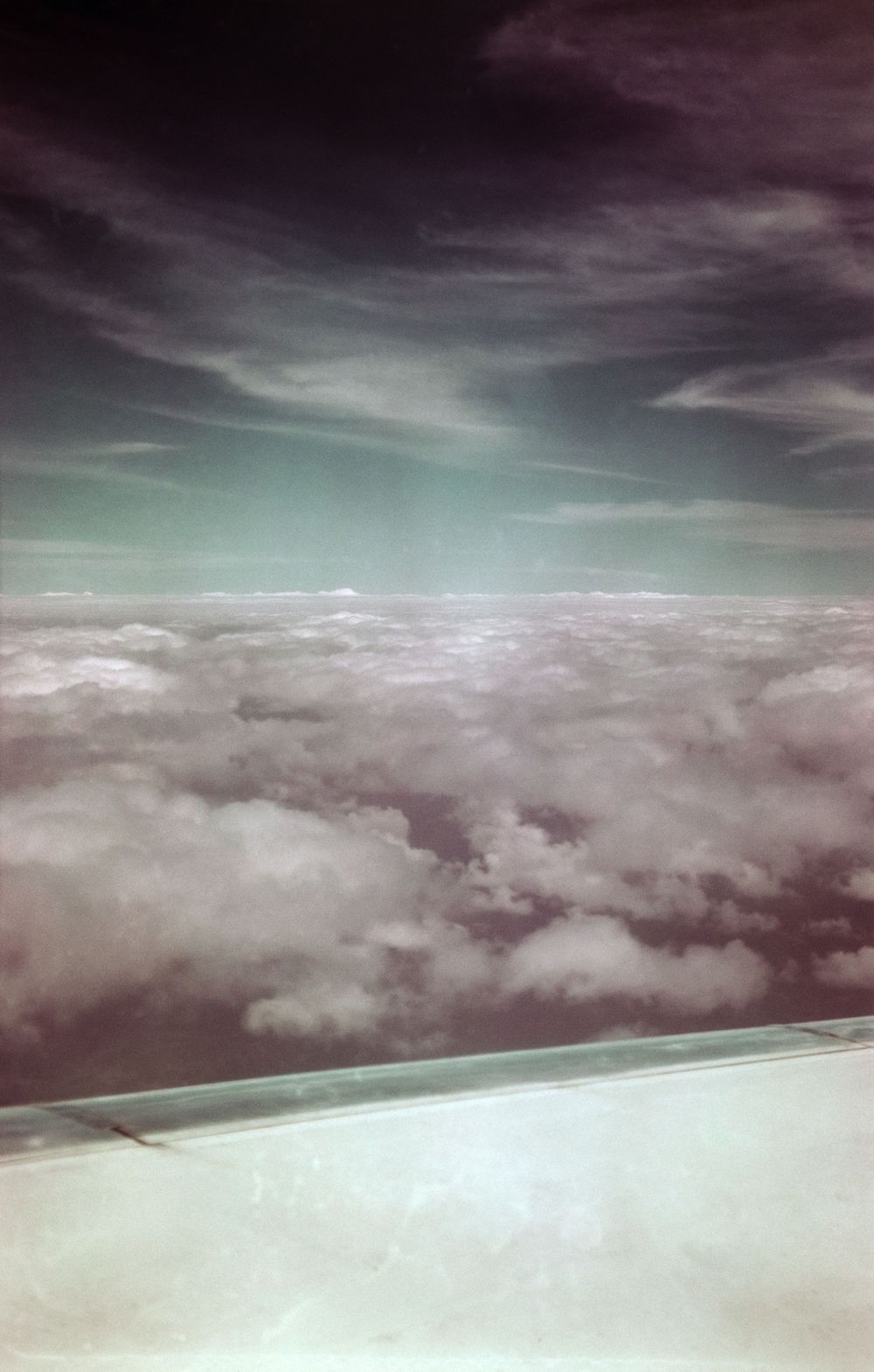 Aerial view of fluffy clouds under a dramatic purple and turquoise sky.