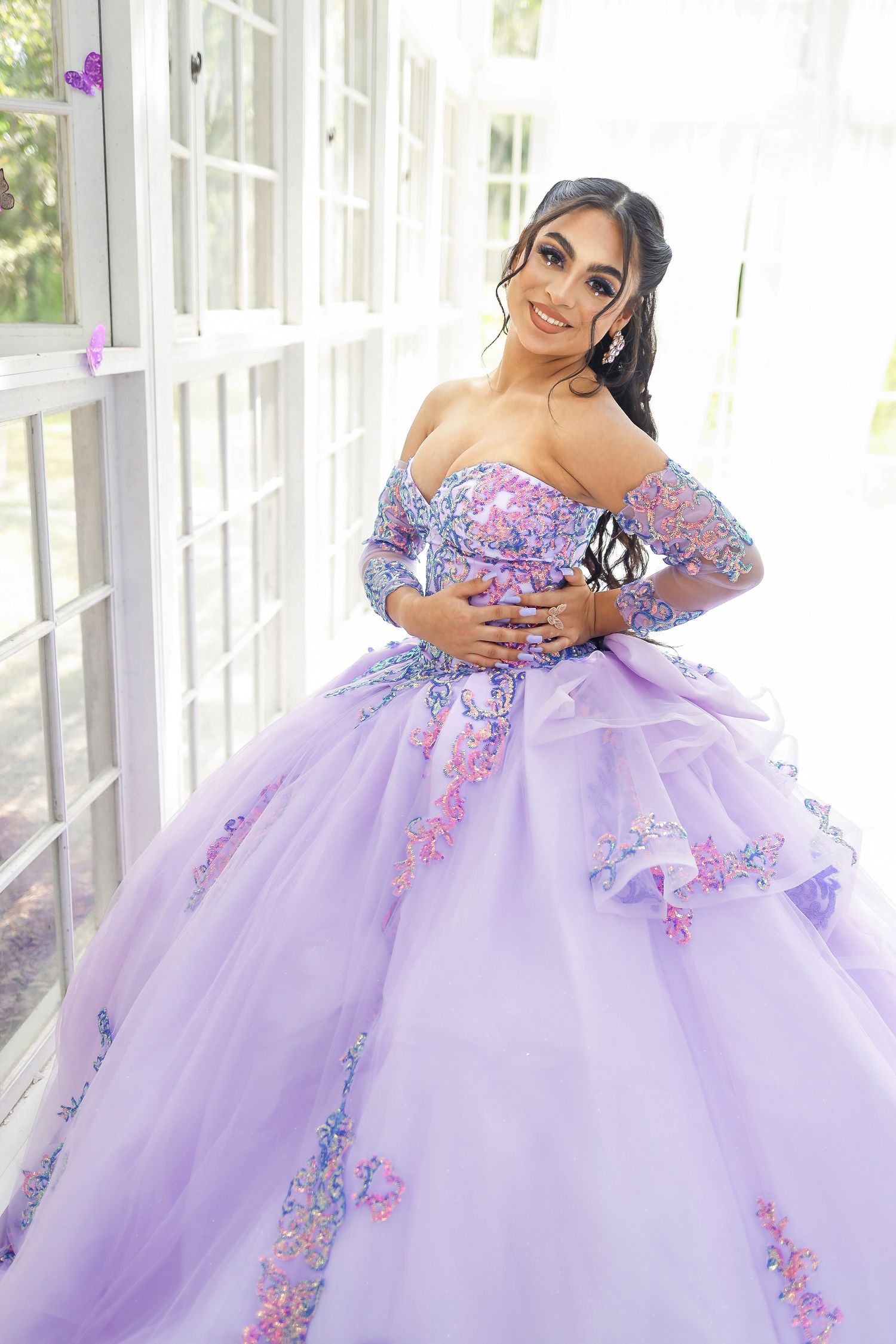Stunning lavender quinceañera dress with floral embellishments in bright sunlit room.