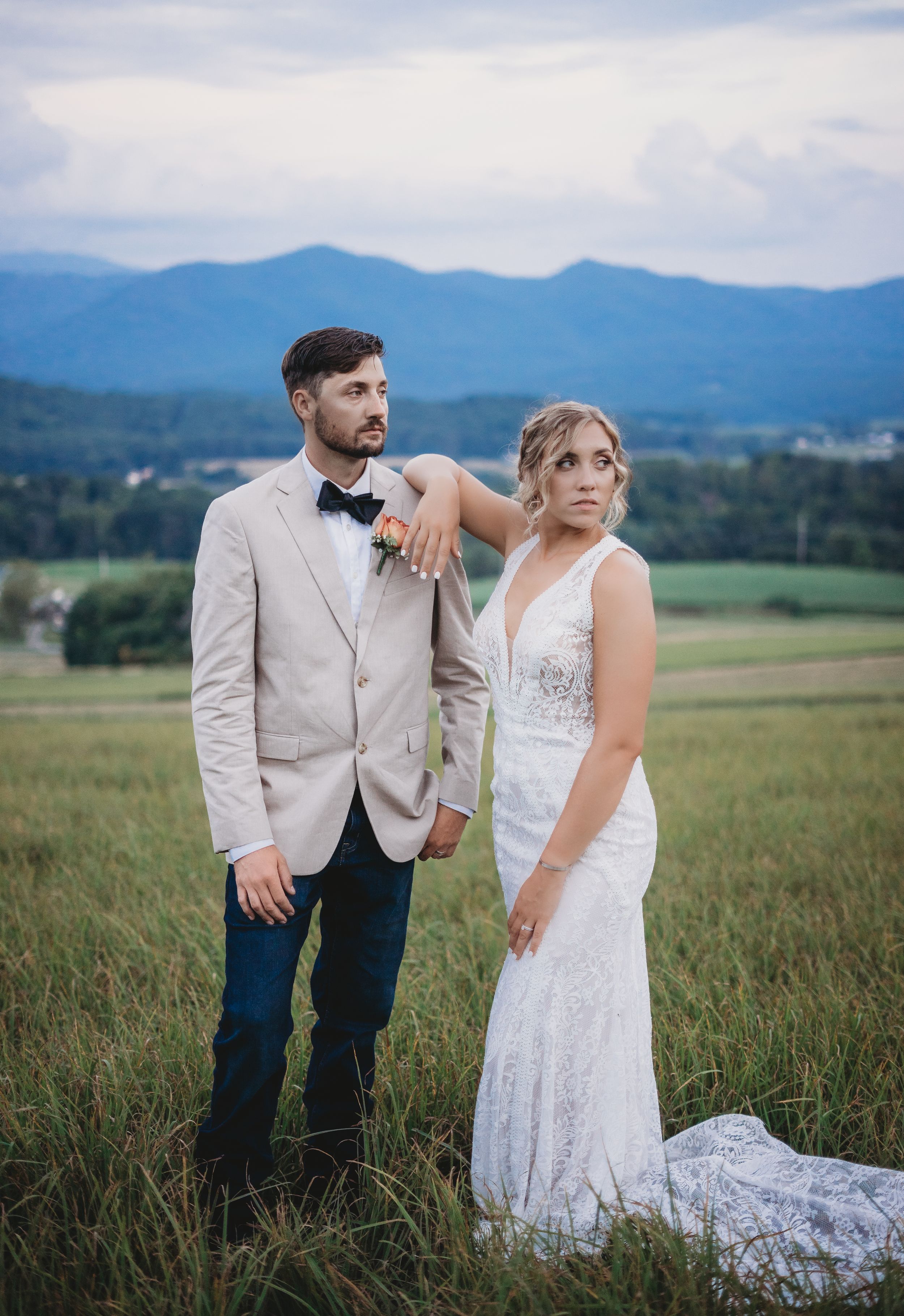 Elegant wedding couple shares intimate moments in mountain field during golden hour.