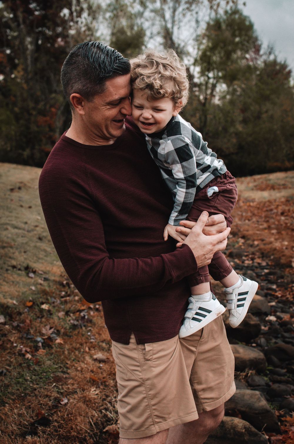 A dad and child laughing together, while the dad holds the child close.