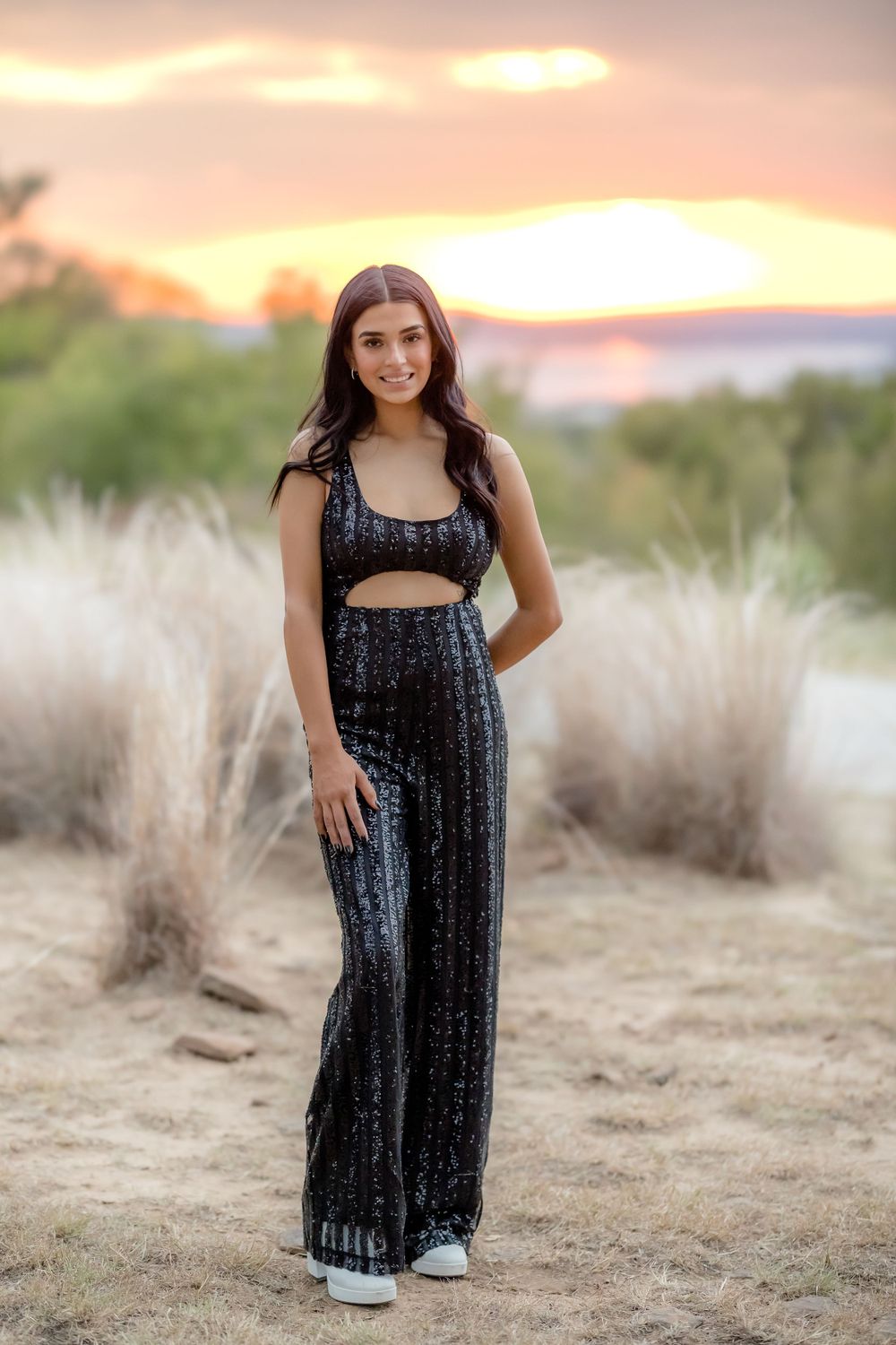 A sparkly black two-piece outfit with palazzo pants photographed at sunset in a desert setting.