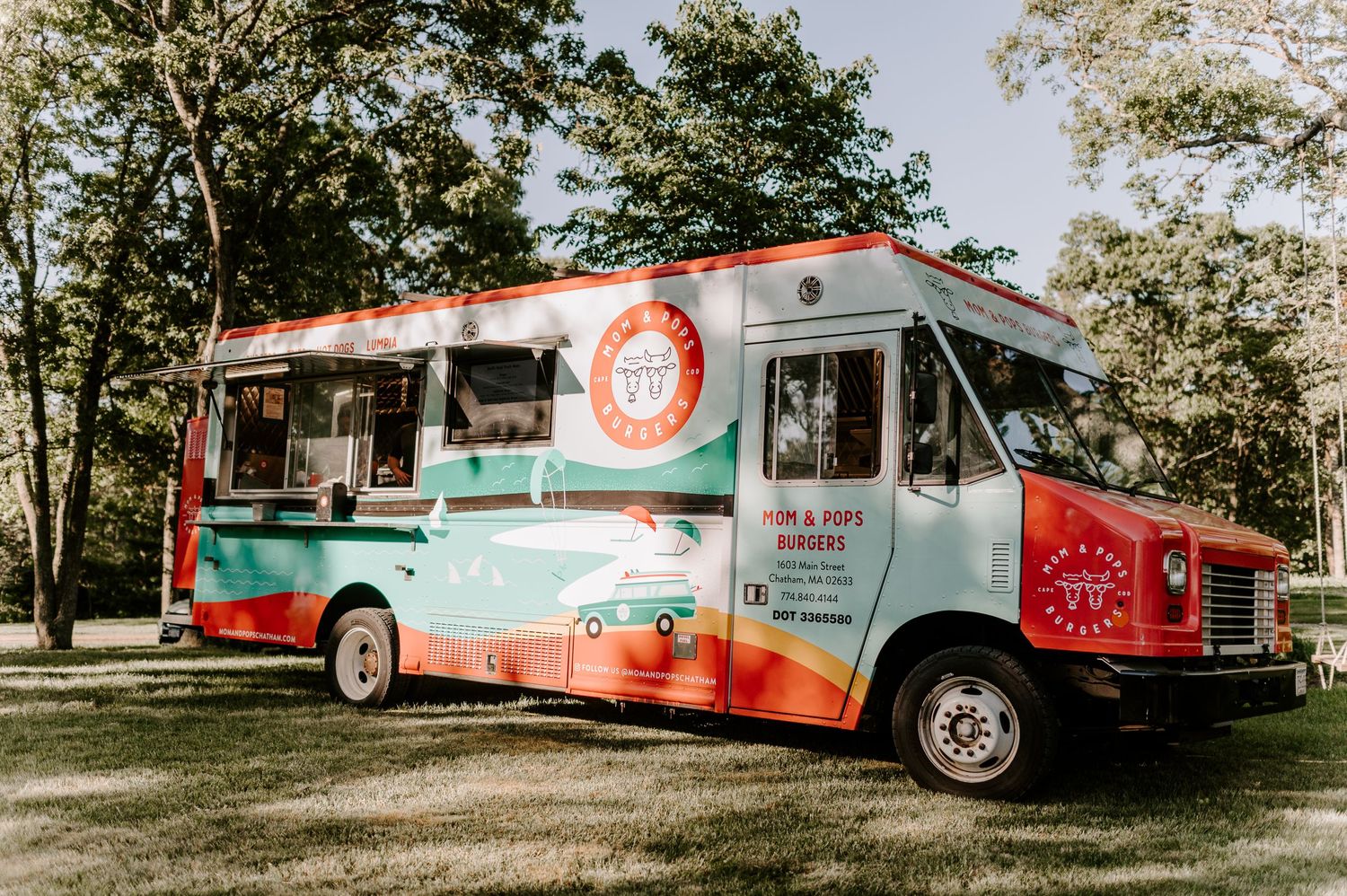 Colorful food trucks parked on grass at outdoor wedding venue.