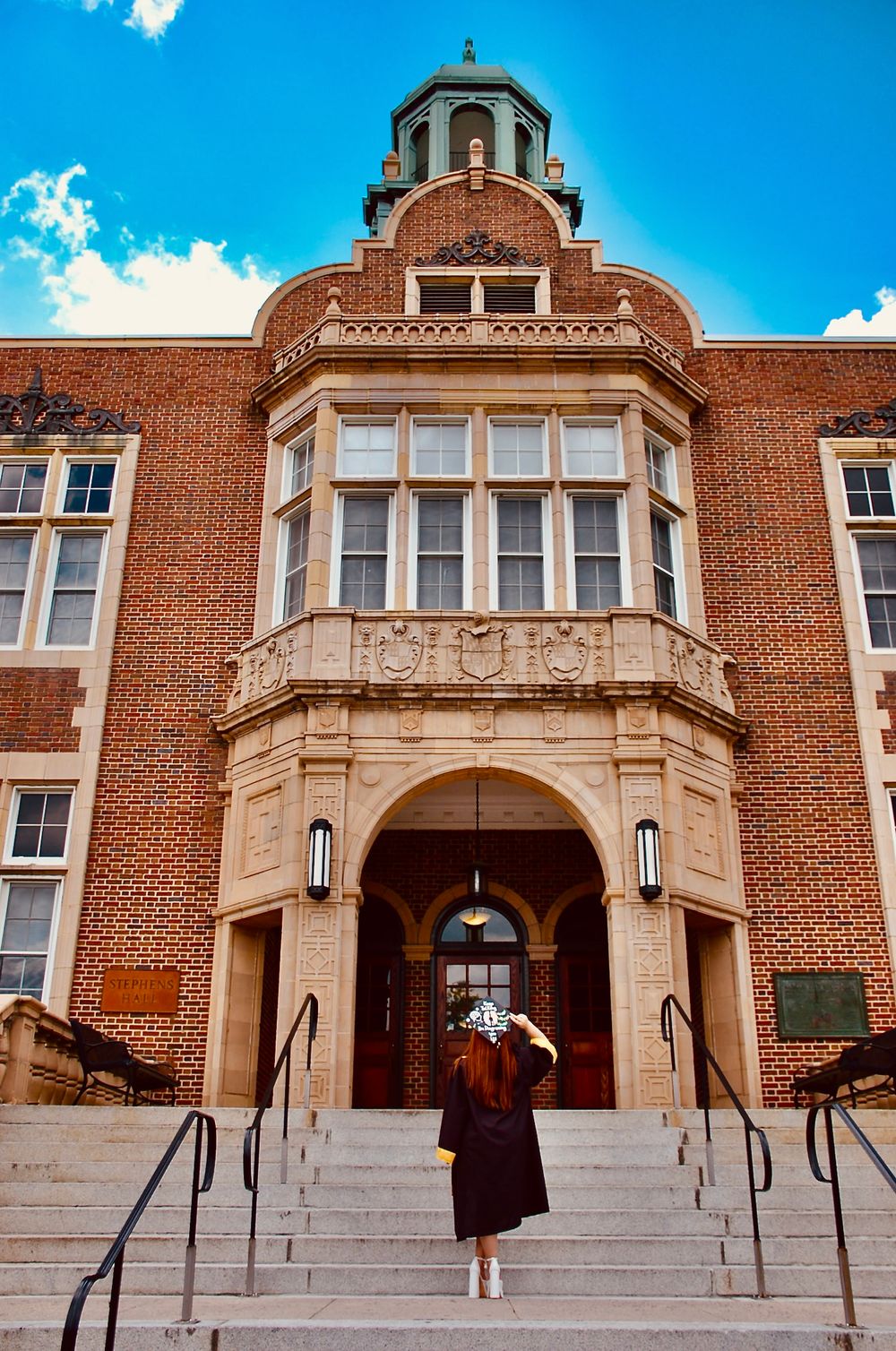 Ornate brick building with domed tower and arched entrance against blue sky.