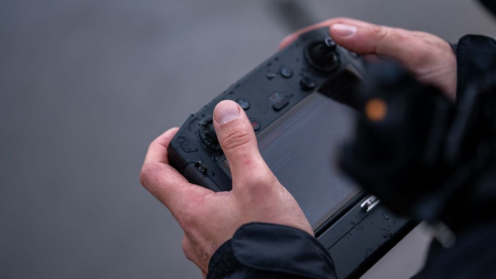 Hands holding a black video game controller against a dark background.