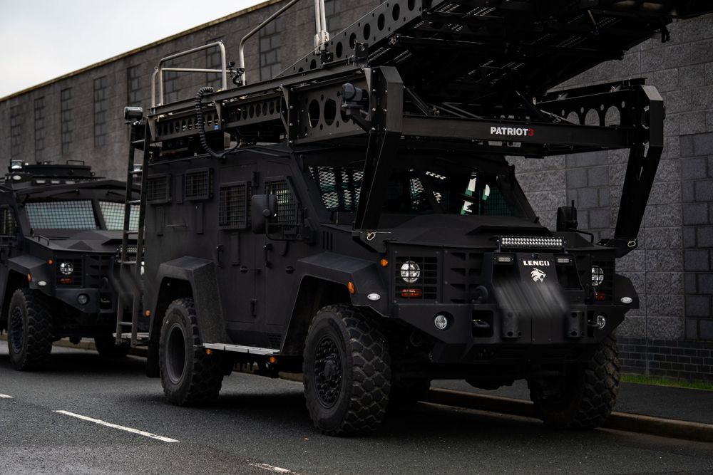 Armored tactical vehicles parked outside building during nighttime operation.