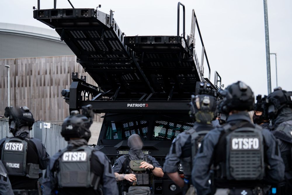 CTSFO team members gathered around tactical vehicle with riot control equipment.