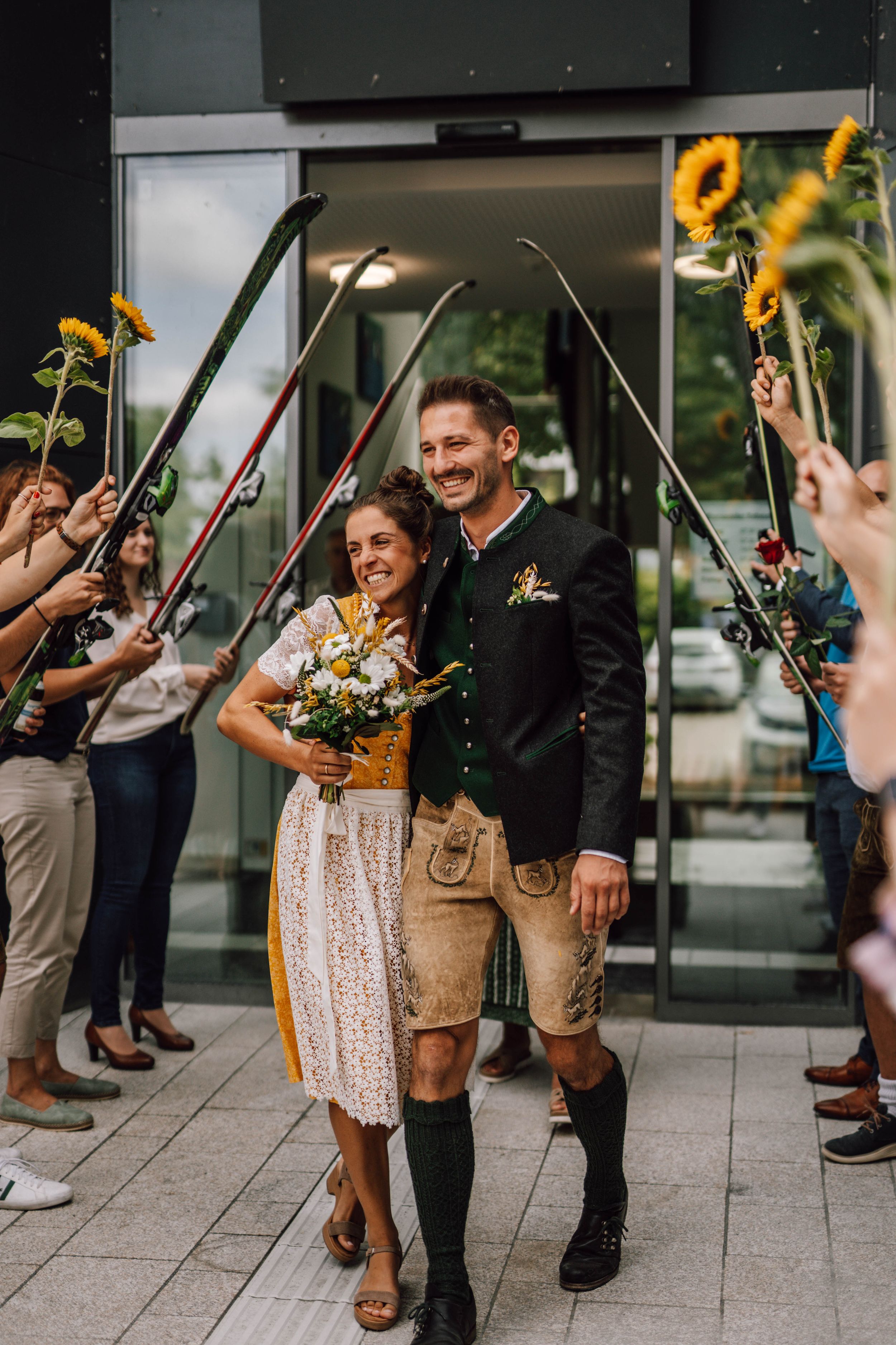 Wedding celebration with traditional dirndl dress and sunflowers on a modern city plaza.