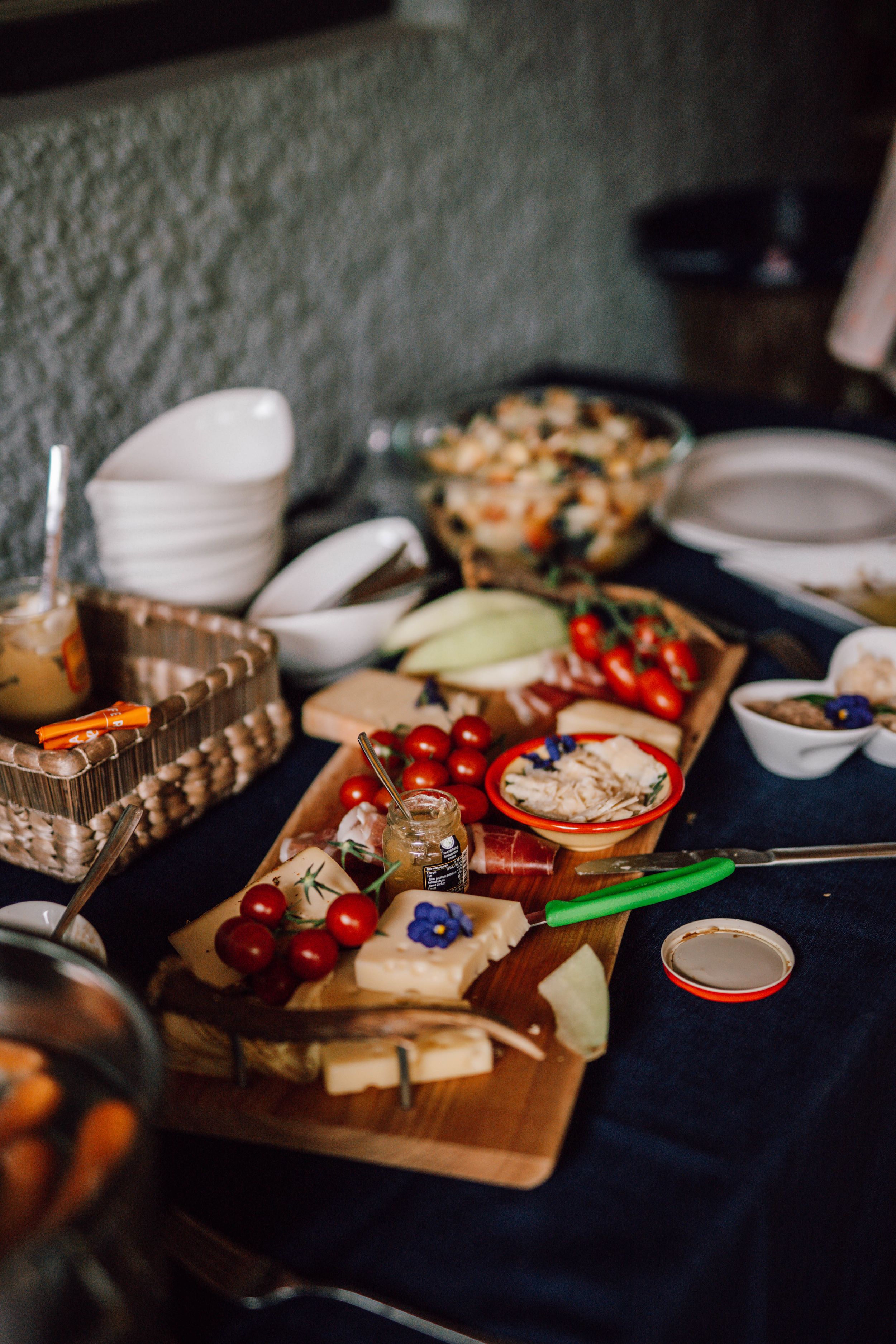 Rustic wedding reception appetizer spread with cheese, fruits and snacks on wooden board.