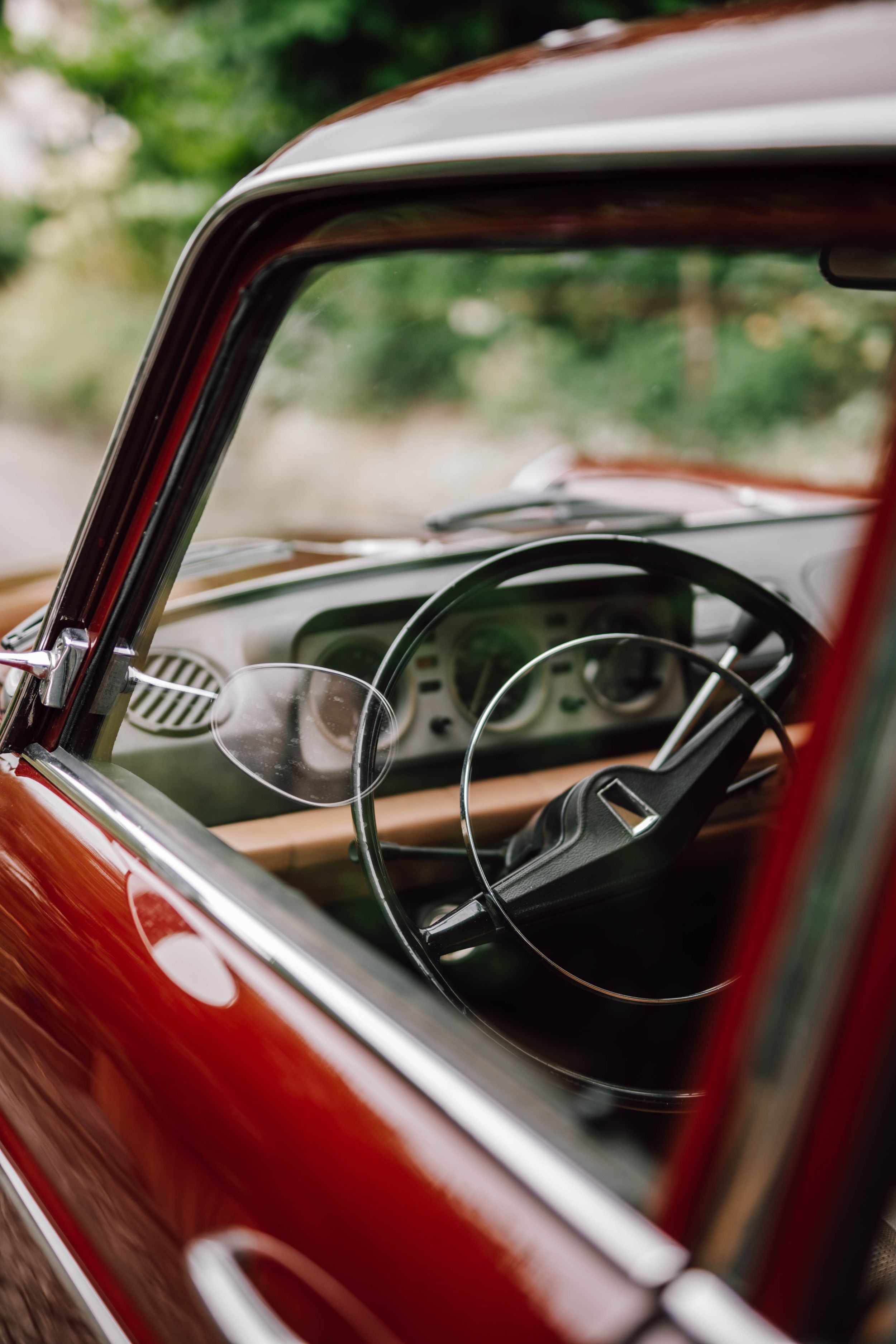 Interior dashboard view of classic vintage car showing steering wheel and gauges.