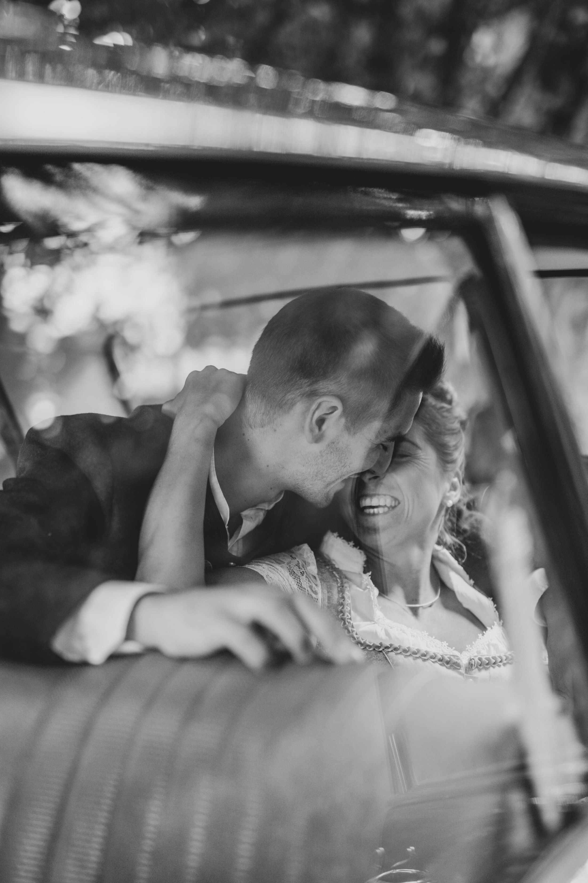 Black and white photo of a couple sharing intimate moments in a car.