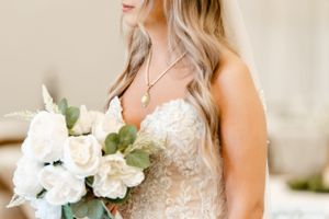 Close-up of a bride holding a white rose bouquet in a lace wedding dress.