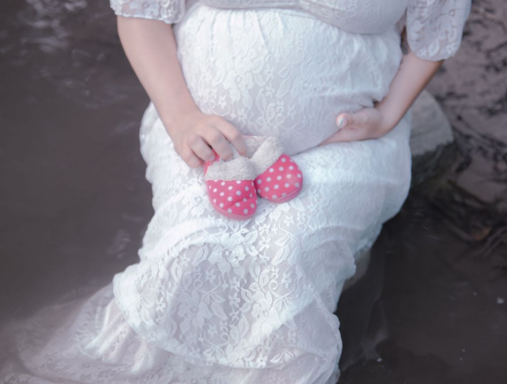 Close-up of a maternity dress with pink accessories by the water.
