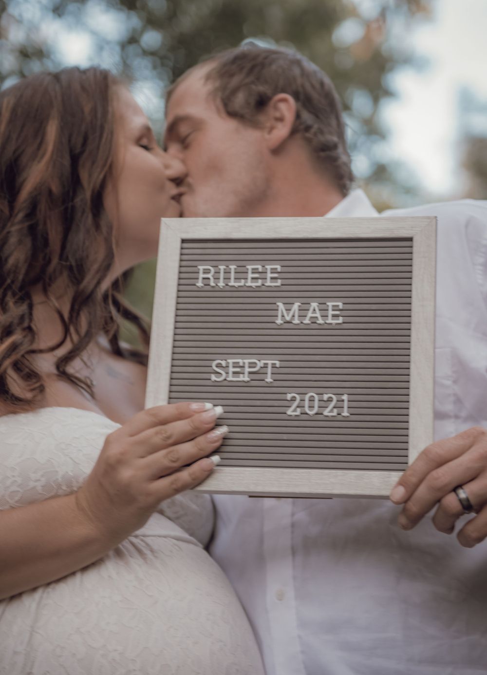 Intimate moment with couple holding letterboard announcing September 2021 arrival.