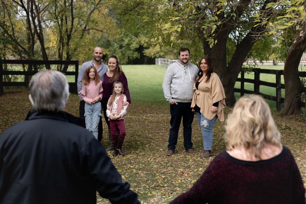 Behind-the-scenes view of family photo session in park setting with fall foliage.