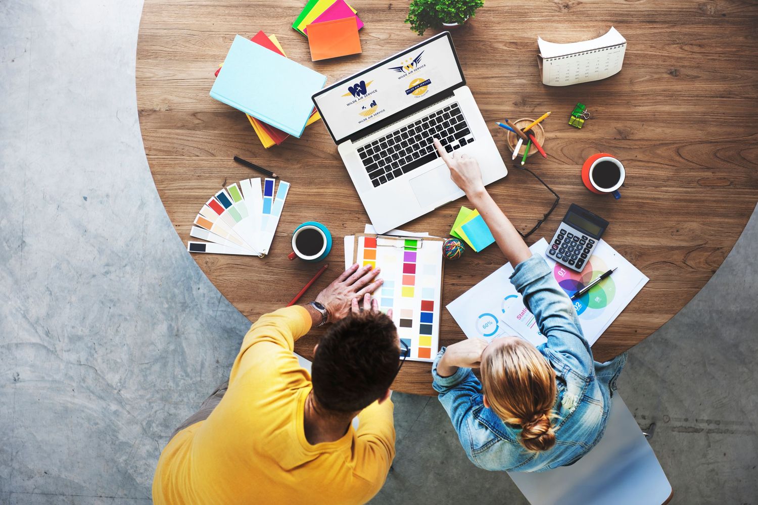 designer and client discussing logo on laptop surrounded by designer tools