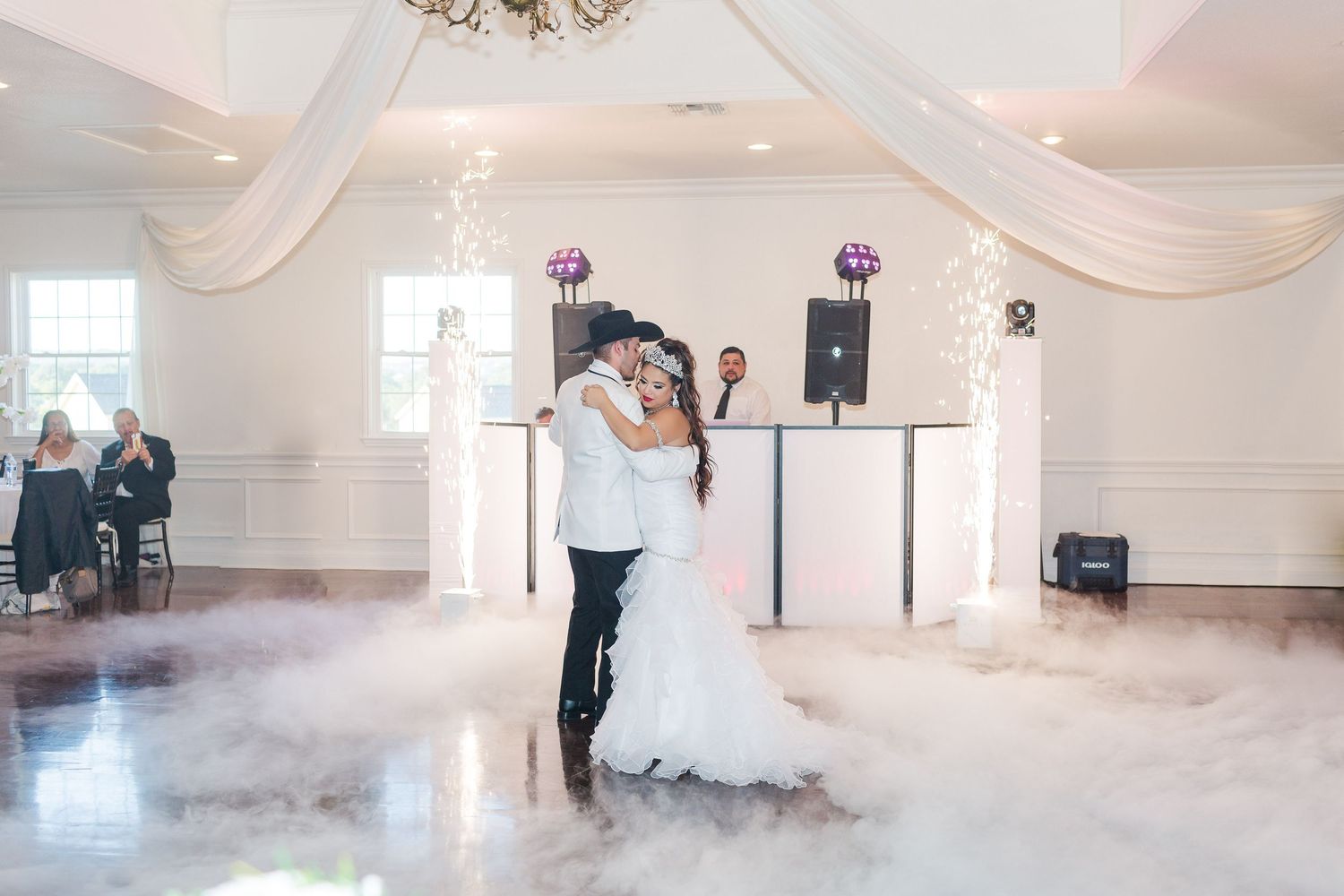 A dreamy wedding reception venue with white decor and ethereal fog effects on the dance floor.