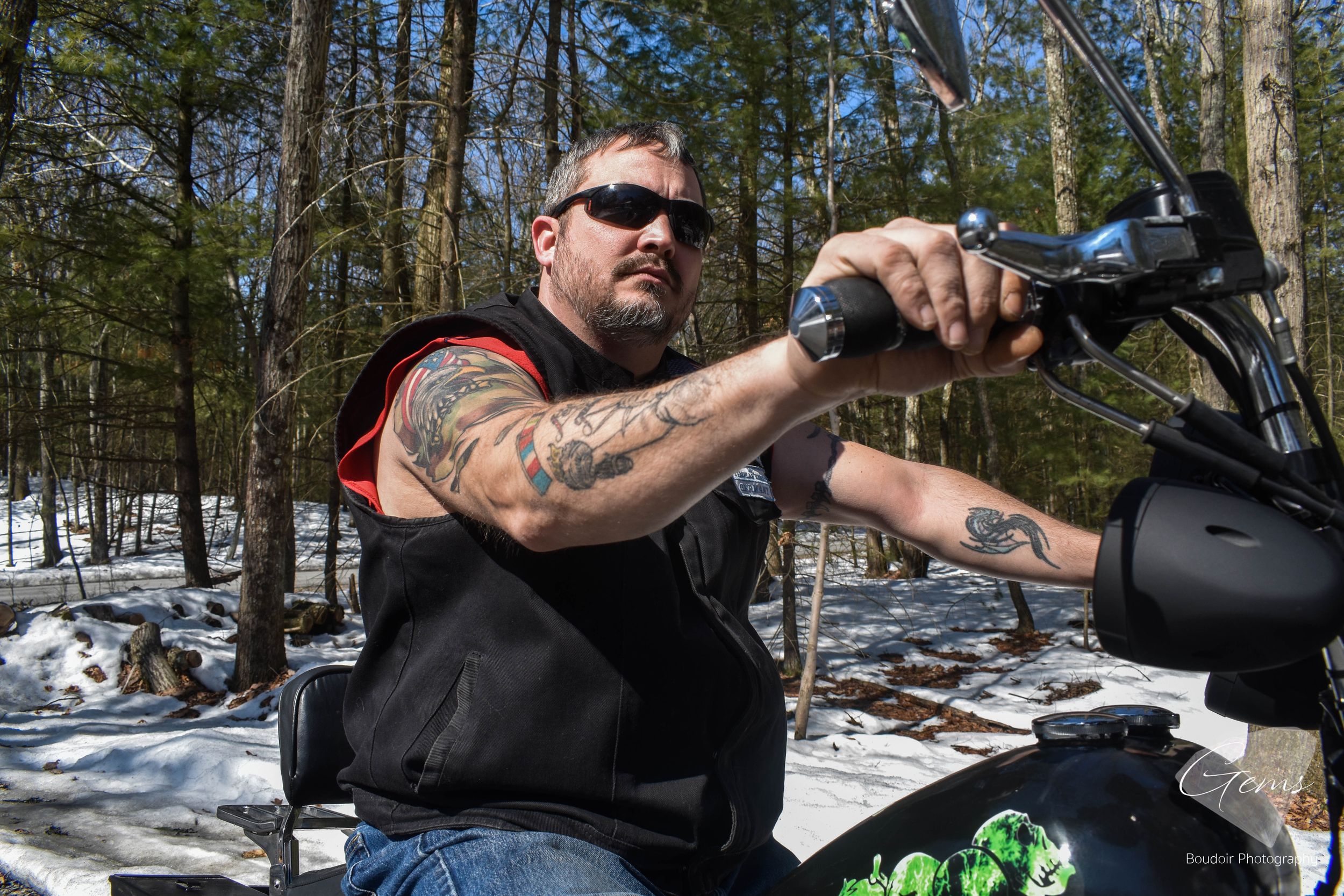 Man in a leather motorcycle vest sitting on his bike, upward angle