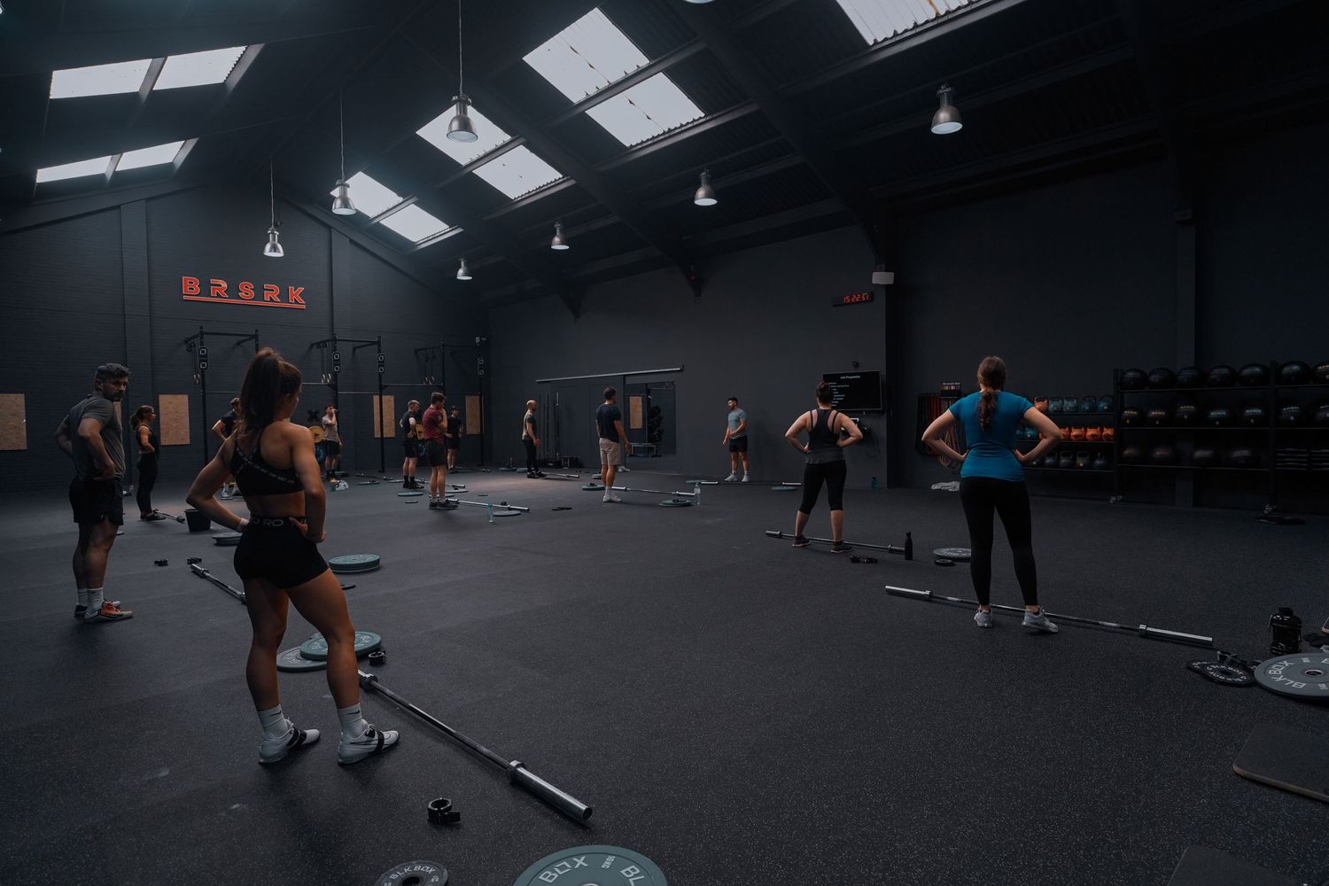 Athletes exercising in a dimly lit indoor gym with weightlifting equipment.