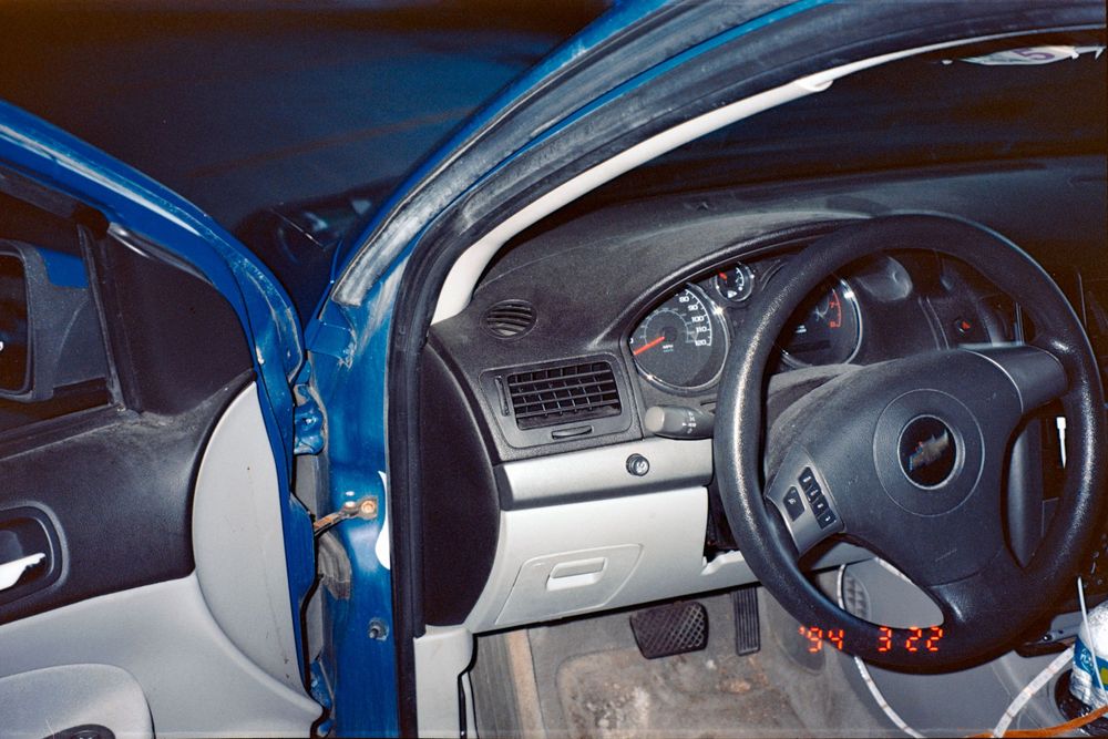 Interior dashboard view of a blue car showing steering wheel and instrument panel.