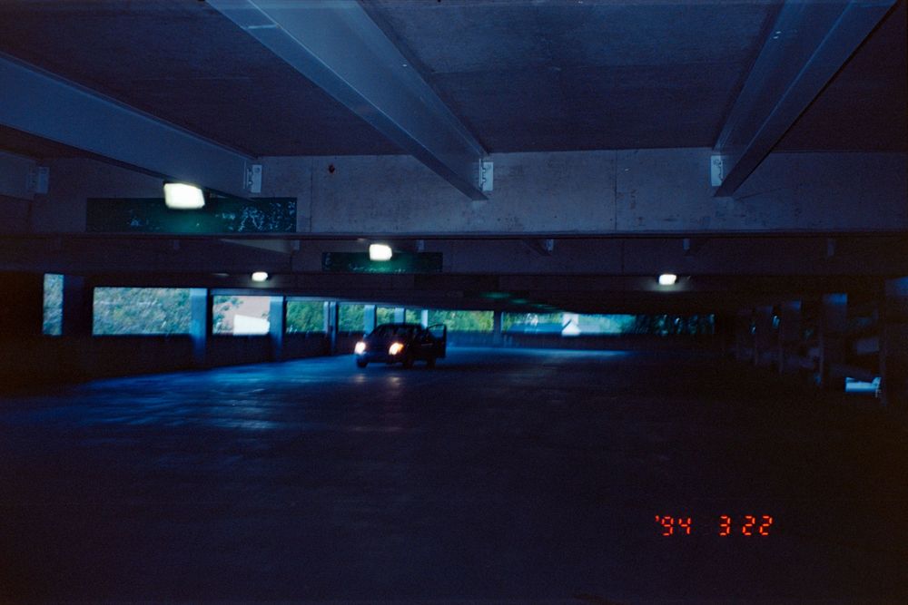 Dimly lit underground parking garage with blue lighting and lone vehicle.