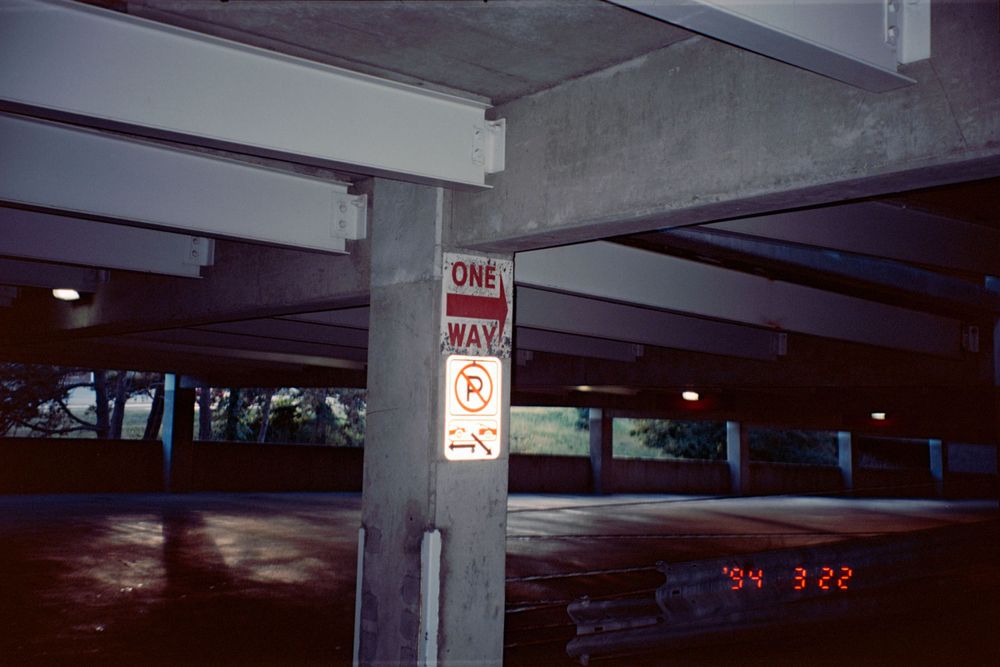 Parking garage pillar with no parking sign in dim lighting.