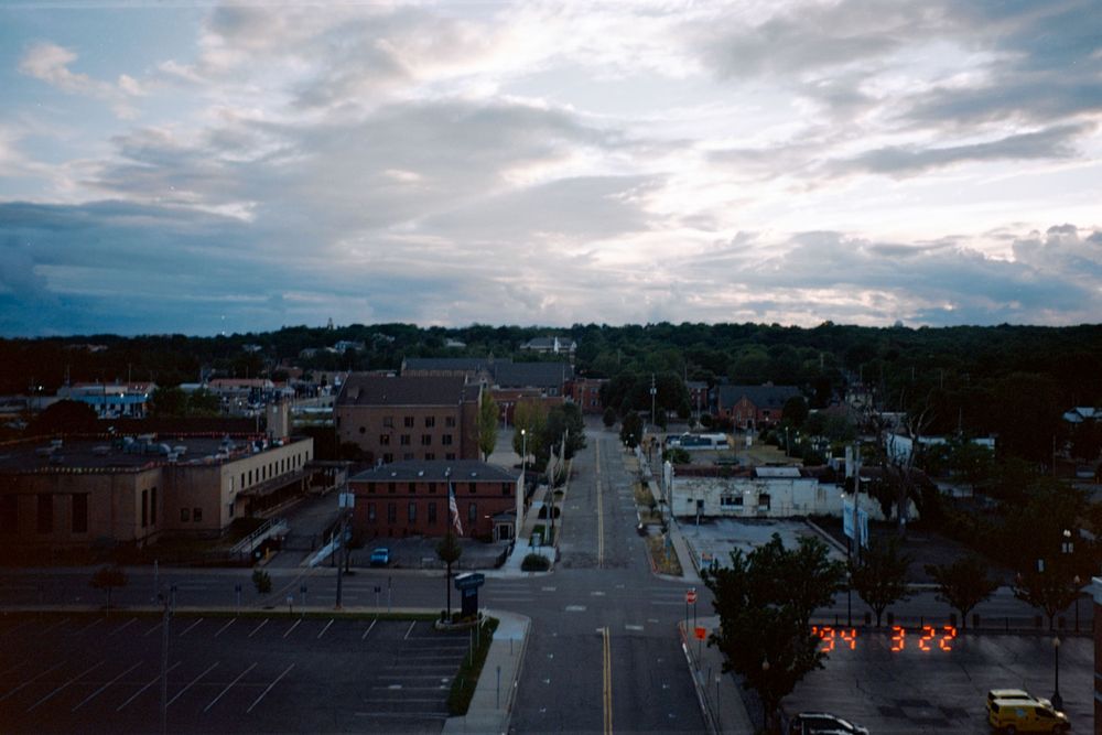 Aerial view of a small town street at dusk with cloudy sky.