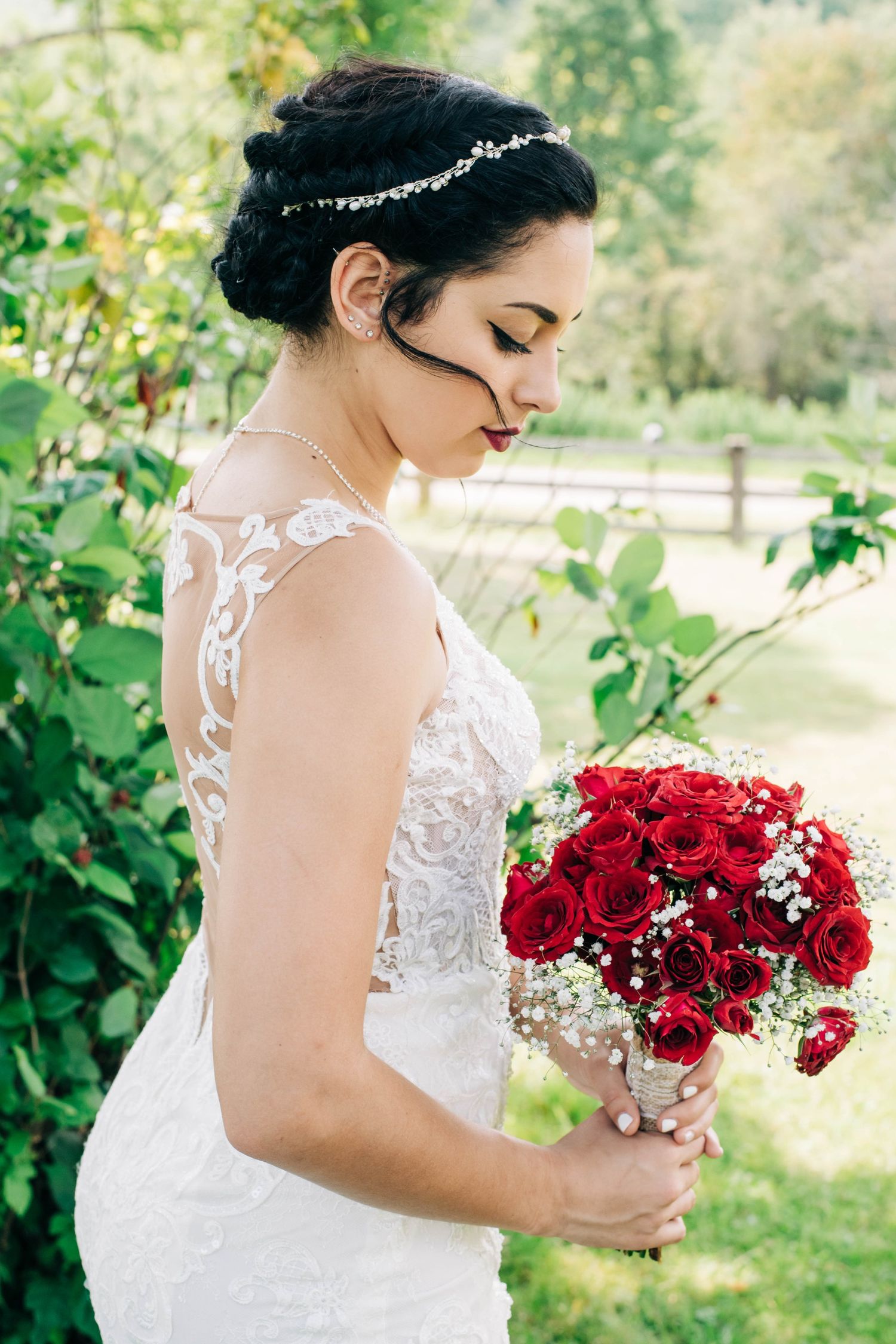 bride looking down at red roses she is holding