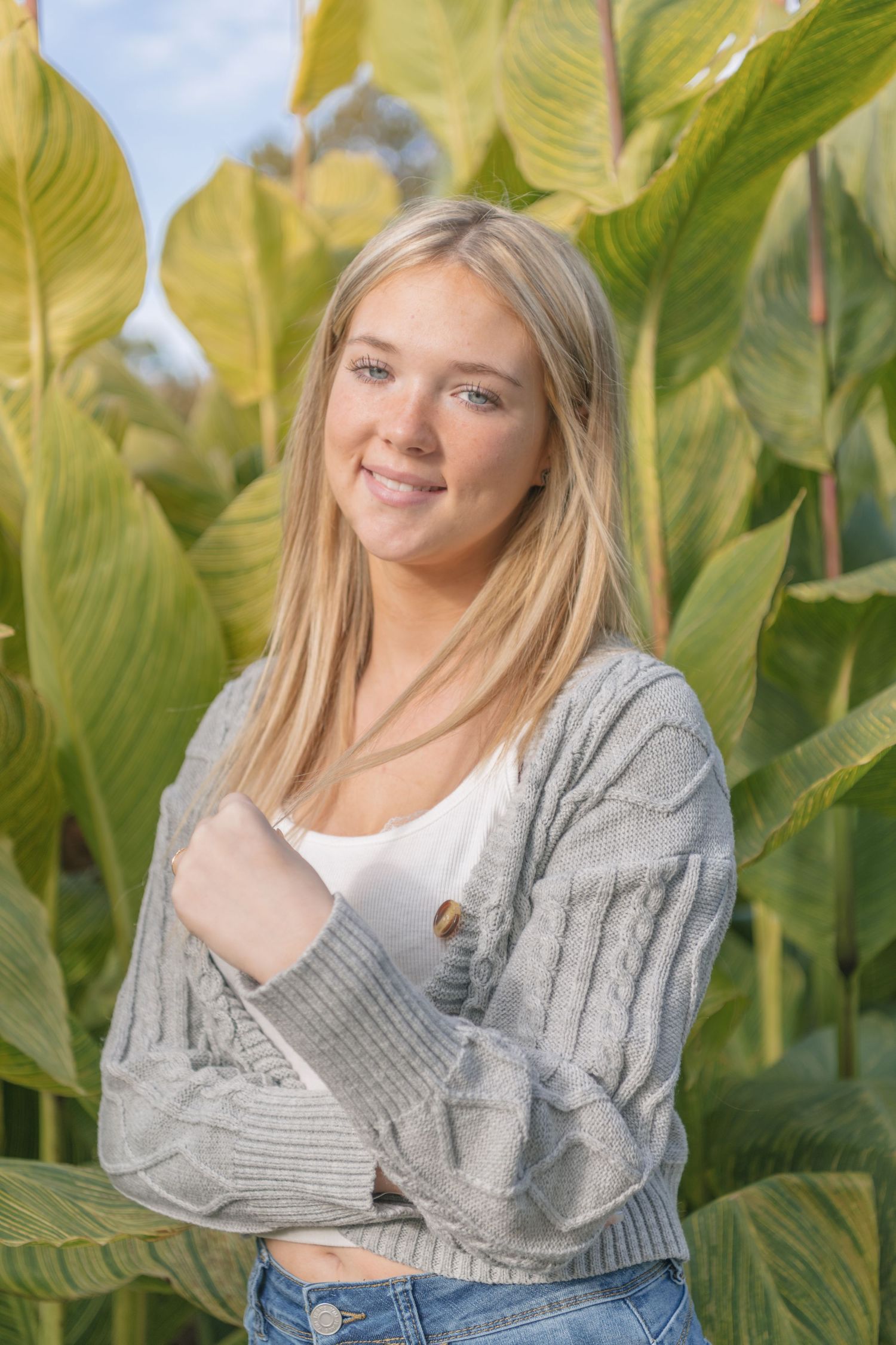 Portrait of someone in a grey cardigan against tropical foliage background.