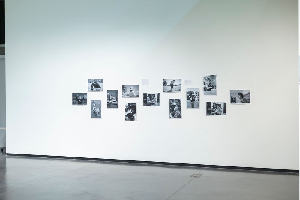 Art gallery wall displaying black and white photographs in a scattered arrangement.