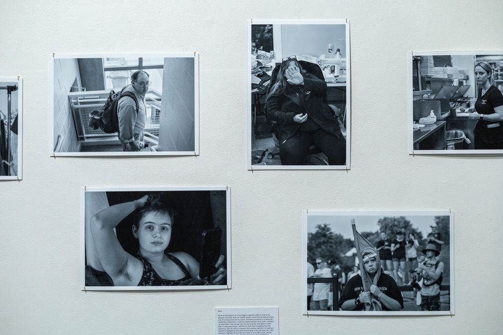 Vintage black and white photographs displayed in a grid formation on a museum wall.