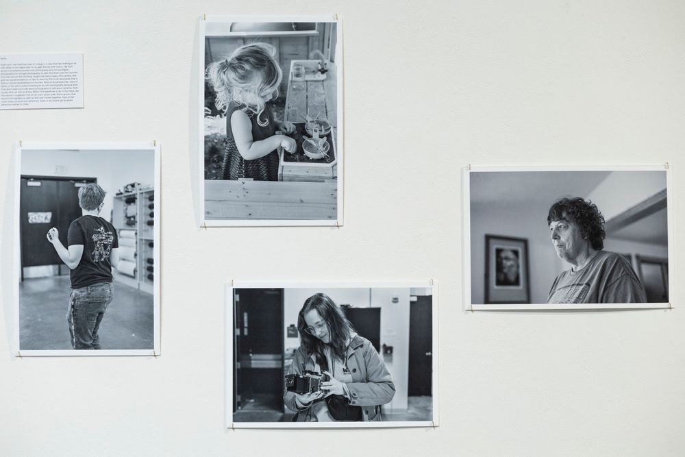 Four black and white photographs arranged on a white wall showing candid moments.