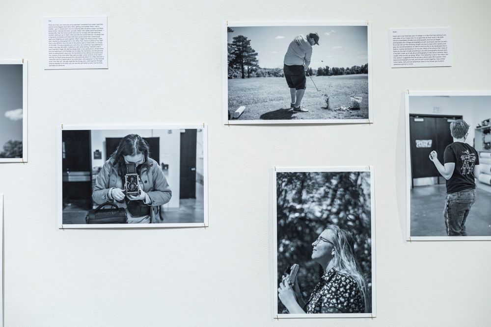 Gallery wall displaying black and white documentary-style photographs with text descriptions.