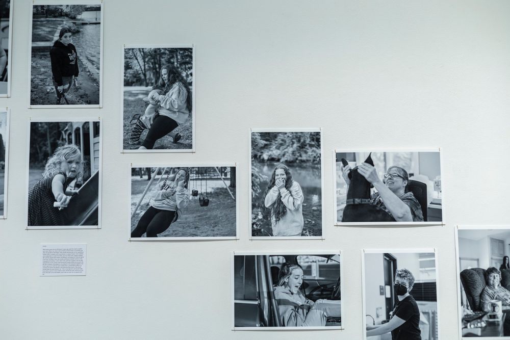 Diagonal arrangement of vintage black and white photographs on a gallery wall.