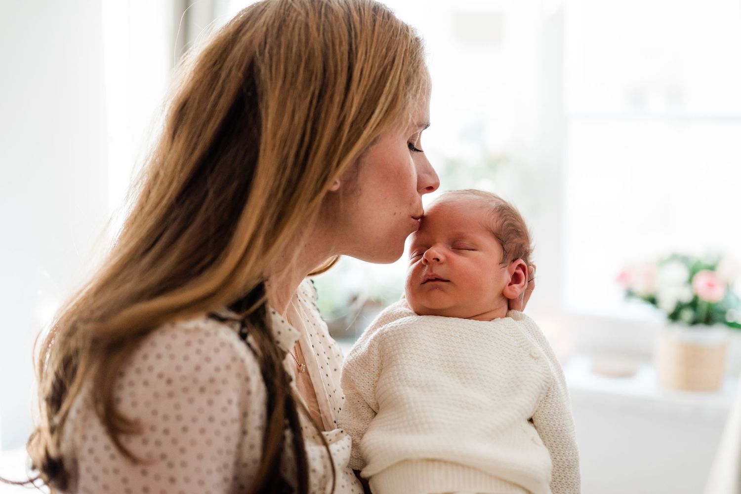 Mother lovingly kissing her newborn son in her home in Rolle, Switzerland