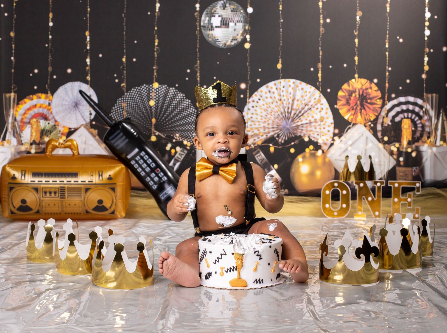 New Year themed cake smash session with gold decorations, disco ball, and party fans.