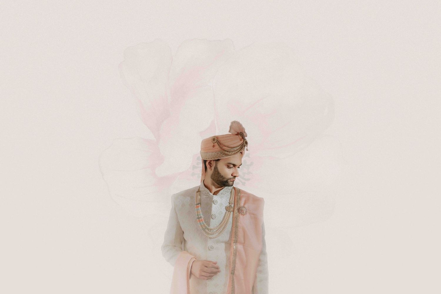 A groom in traditional Indian attire poses against a minimal light background.