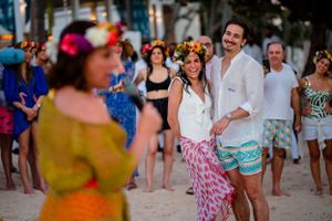 Beachside celebration with colorfully dressed guests dancing in the sand.